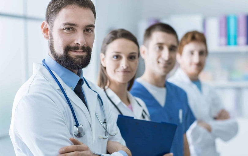 a doctor smiling confidently with 3 nurses in the background